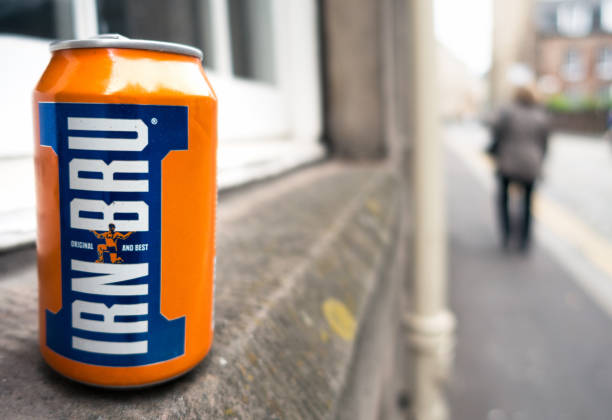 Edinburgh, Scotland, UK - An empty can of Irn Bru, the popular Scottish soft drink, discarded on a street in central Edinburgh, with a pedestrian in the background.