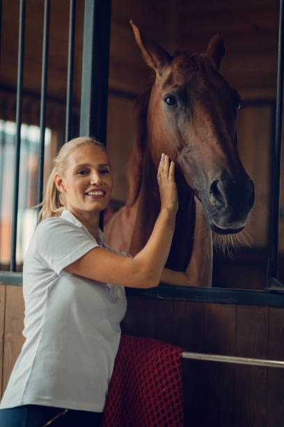 Woman in a barn with her horse Woman in a barn with her horse. She is stroking him and smiling. 8571 stock pictures, royalty-free photos & images