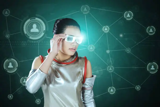 Young woman wearing a modern costume while looking at social network icons on the futuristic glasses