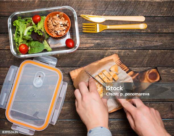 Woman Preparing Takeaway Meal For Her Child School Lunch Box With Salad Fried Chicken And Nuts On Rustic Wooden Background Healthy Eating Habits Concept Stock Photo - Download Image Now