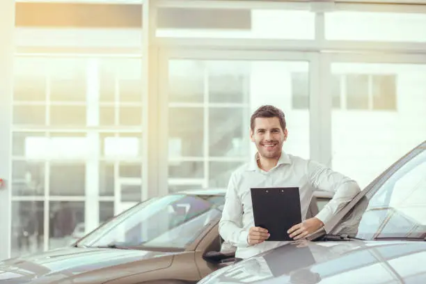 Young man in a car rental service holding contract