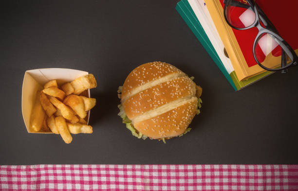 Books and hamburger on the dining table with eye glasses Books and hamburger on the dining table with eye glasses beef pad stock pictures, royalty-free photos & images