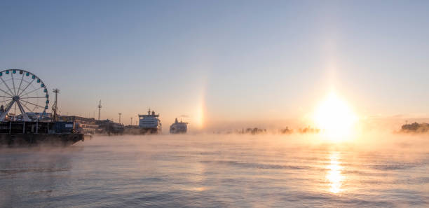 A frozen winter sunrise at Helsinki harbour with sundogs. The sea is steaming.