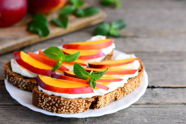 istock Bright sandwiches with cream cheese, fresh nectarines slices, walnuts and mint on a serving plate and on a vintage wooden table. 839178806