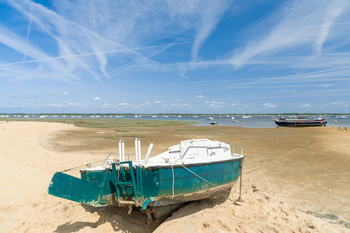 Arcachon Bay, France - August 19, 2017: boats at low tide on the beach of Claouey, near the Cap Ferret, one of the 23 oyster villages of the Arcachon Bay.