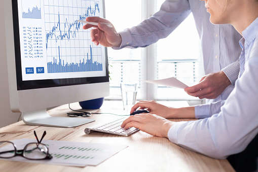 Team of traders working with forex (foreign exchange) trading charts and graphs on computer screen, concept about stock market investment, finance, selling and buying