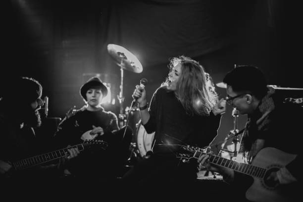 Young music rock band on the stage. Teenage group are making music, and are in love with it. Shoot with artificial light and stage light inside. The group of young people, are shoot in Denmark in black and white, B&W. The teenagers are singing, jumping and playing on their instruments.