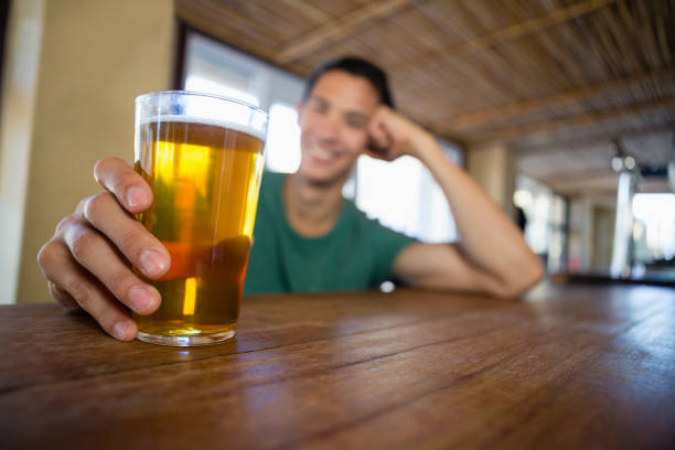 Smiling man holding beer glass at counter in restaurant