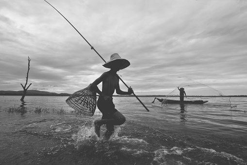 Fisherman boy and his granfather catching fish with equipment, Black and White vintage film tone, Lifestyle and leisure concept, occupation concept, Split tone pinterest and instragram like process.