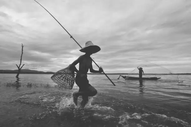 Photo of Fisherman boy and his granfather catching fish with equipment, Black and White vintage film tone, Lifestyle and leisure concept, occupation concept, Split tone pinterest and instragram like process.