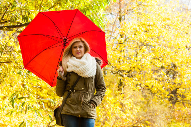 istock Woman walking in park with umbrella 839258102