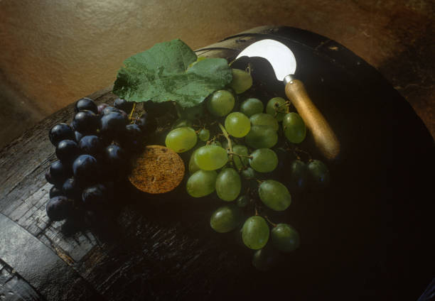 close up on green grapes and a knife on wine barrel