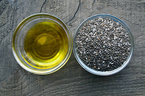 Chia oil with chia seeds in a glass bowls on old wooden background.Organic chia seed oil.Healthy food,superfood or bodycare concept. Chia oil with chia seeds in a glass bowls on old wooden background.Organic chia seed oil.Healthy food,superfood or bodycare concept.Selective focus. chia seed photos stock pictures, royalty-free photos & images