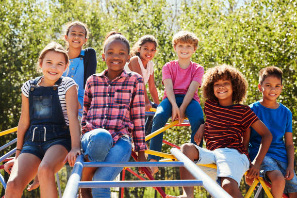 Pre-teen friends sitting on climbing frame in playground Pre-teen friends sitting on climbing frame in playground jungle gym stock pictures, royalty-free photos & images