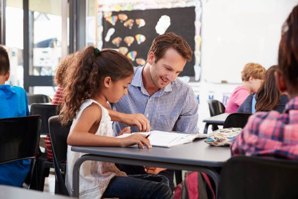 istock Teacher working with young schoolgirl at her desk in class 839297122