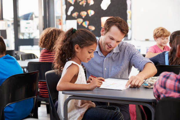 젊은 여 학생와 클래스에서 그녀의 책상에서 일 하는 교사 - teacher child student education 뉴스 사진 이미지