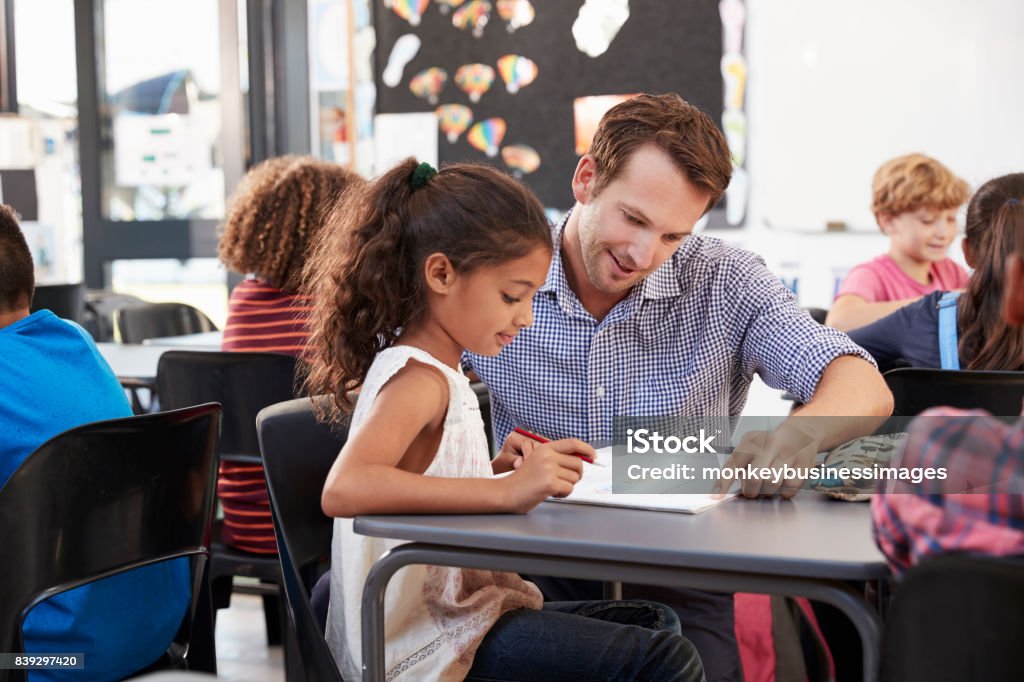Teacher working with young schoolgirl at her desk in class Teacher Stock Photo