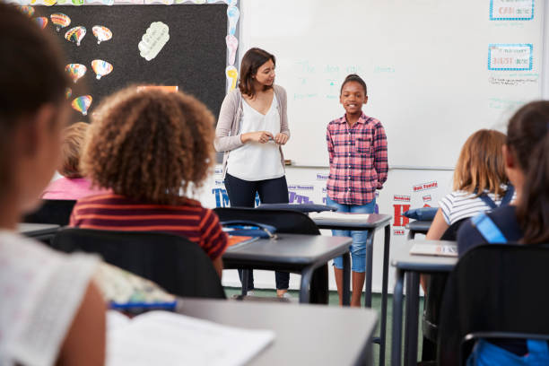 istock Teacher and pupil stand at front of elementary school class 839314868