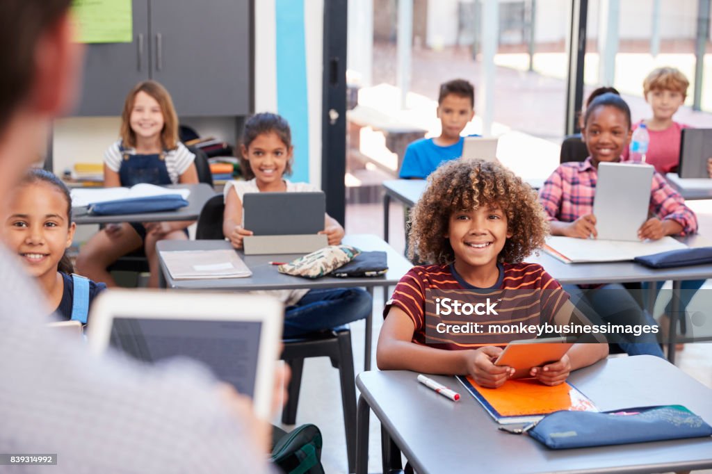 Elementary students looking at teacher, over shoulder view Classroom Stock Photo