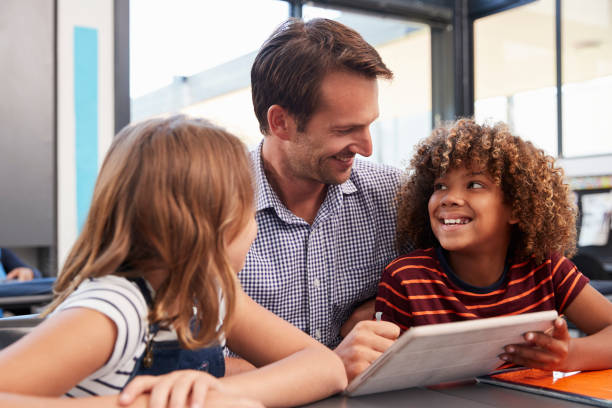 istock Teacher and two pupils in school class looking at each other 839316568