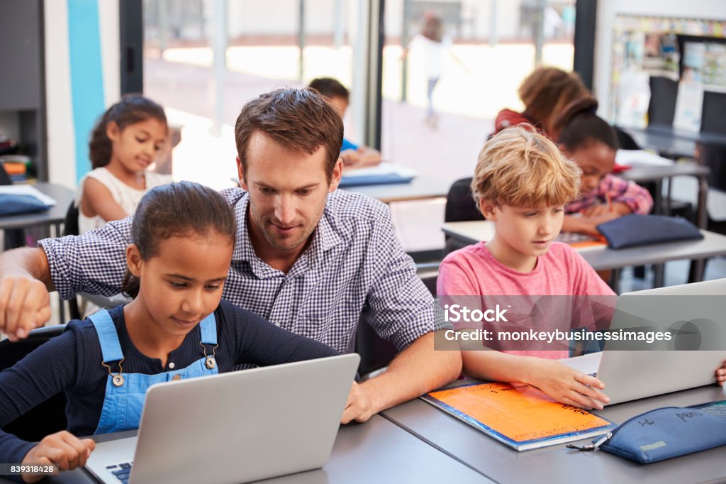 Lehrer, die Unterstützung der jungen Schüler mit Laptops in Klasse - Lizenzfrei Lehrkraft Stock-Foto