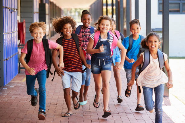 School kids running in elementary school hallway, front view School kids running in elementary school hallway, front view pre adolescent child stock pictures, royalty-free photos & images