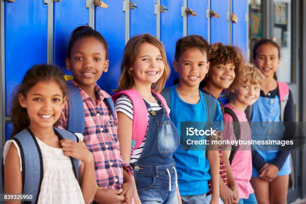 Niños De La Escuela Frente De Armarios En El Pasillo De La Escuela Primaria Foto de stock y más banco de imágenes de Niño