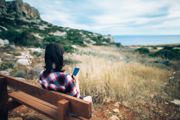 女人用她的手機坐在長凳上美麗的山谷 - scotland cyprus 個照片及圖片檔