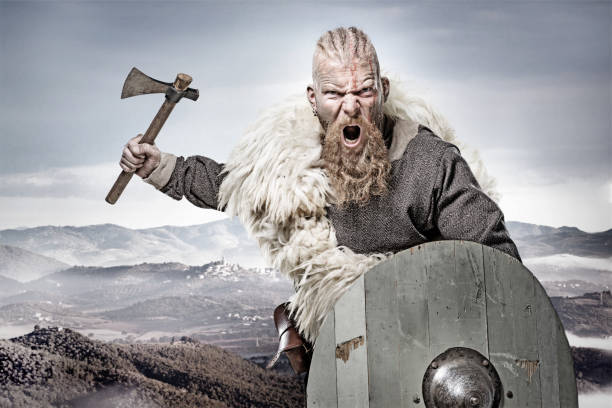 Weapon wielding bloody viking warrior in emotional pose against mountain range Weapon wielding bloody viking warrior in emotional pose against mountain range armory photos stock pictures, royalty-free photos & images