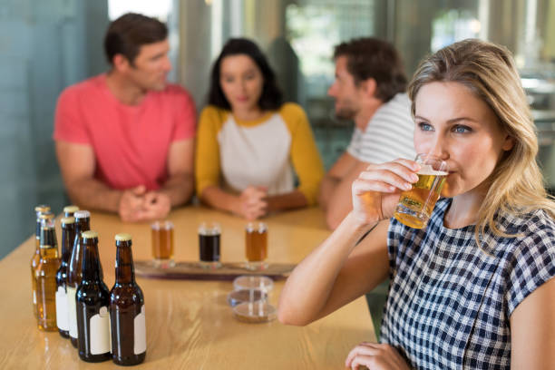 istock Woman having beer while friends standing in background 839352384