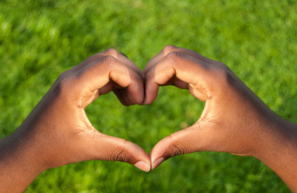 istock Black hands in heart shape with grass background 839352596