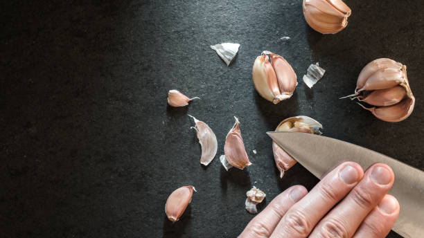 Peeling the garlic with a knife stock photo