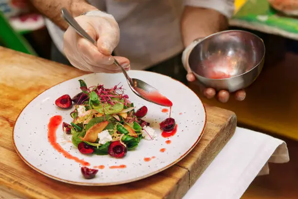 Photo of Chef is adding sauce to vegetable appetizer, toned