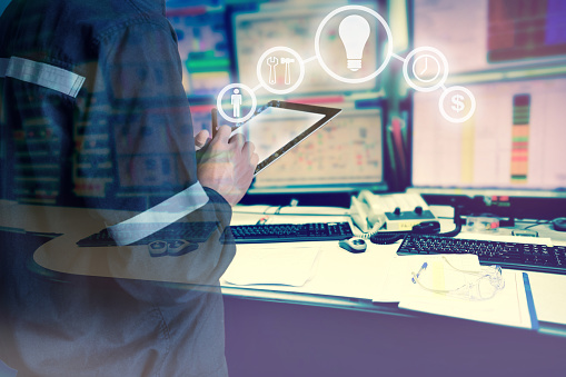 Double exposure of Engineer or Technician man with business industrial tool icons while using tablet with monitor of computers room  for oil and gas industrial business concept.