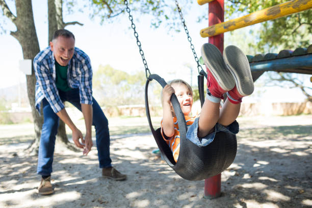 istock Happy father pushing son sitting on swing 839364104