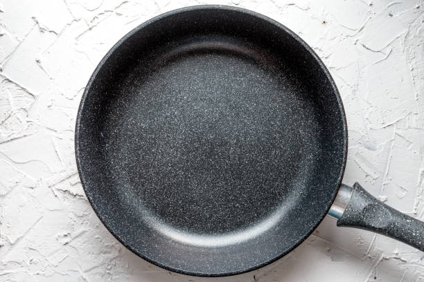 Aluminum frying pan with non-stick coating on white salt stock photo