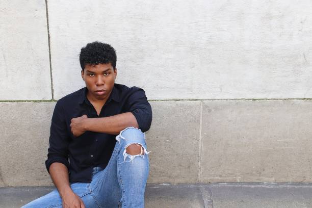 istock Young man sitting outside against concrete wall worried, upset, stressed 839372040