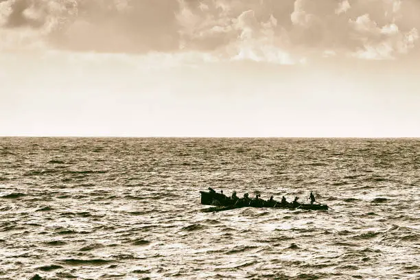 Oarsmen rowing on sea on trainera with vintage filter effect