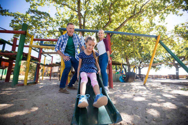 istock Low angle view of happy parents looking at daughter sliding 839372726