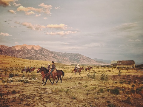 Cowboys bringing back horses at dusk