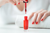 Close-up of red nail polish drop  wih woman nails on backbround