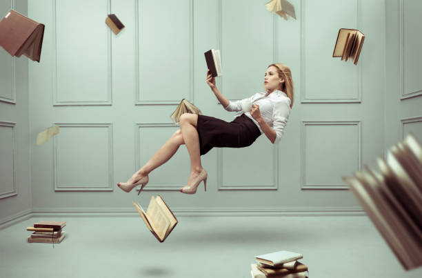 a relaxed woman levitates in a room full of flying books - witch beauty beautiful women imagens e fotografias de stock