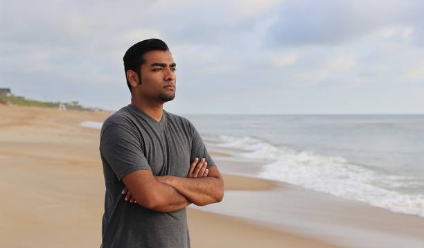 istock Determined man standing with arms crossed on beach 839388930