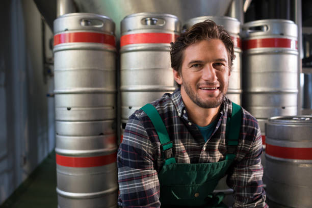 istock Smiling male worker sitting by kegs at warehouse 839391890