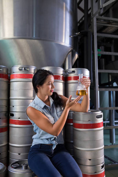 istock Female worker examining beer in beaker at factory 839391984