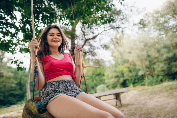 Smiling young african american woman swinging in park