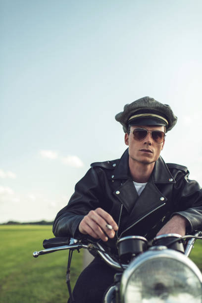 istock Vintage biker smoking cigarette in rural summer landscape. 839518962