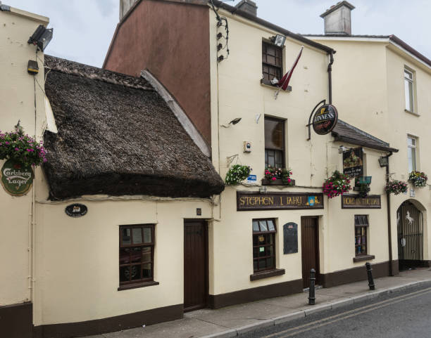 Galway, Ireland - August 3, 2017: The Hole in the Wall Bar shows yellow facade of old house with port and straw roof.
