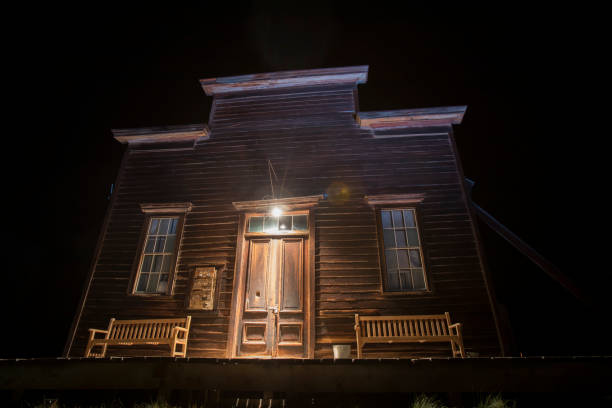 Old dilapidated wooden mansion at night against the background of the moon - Ominous illustration of a creepy house.