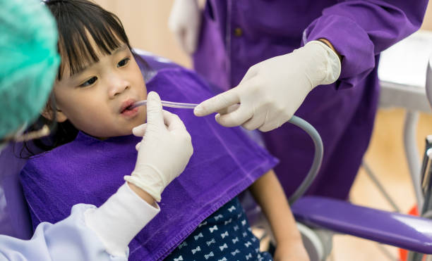 istock Dentist and assistant checking and cleaning Asian girls teeth using suction machine in the dentists chair. 839584266